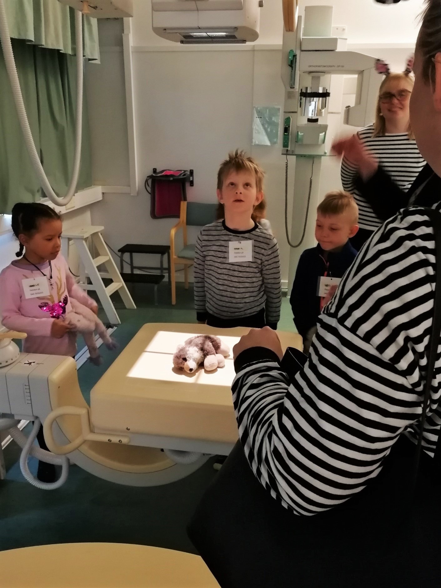 Röntgenhoitajaopiskelijat ja vierailulla olleita lapsia asettelemassa nallea natiivikuvausta varten