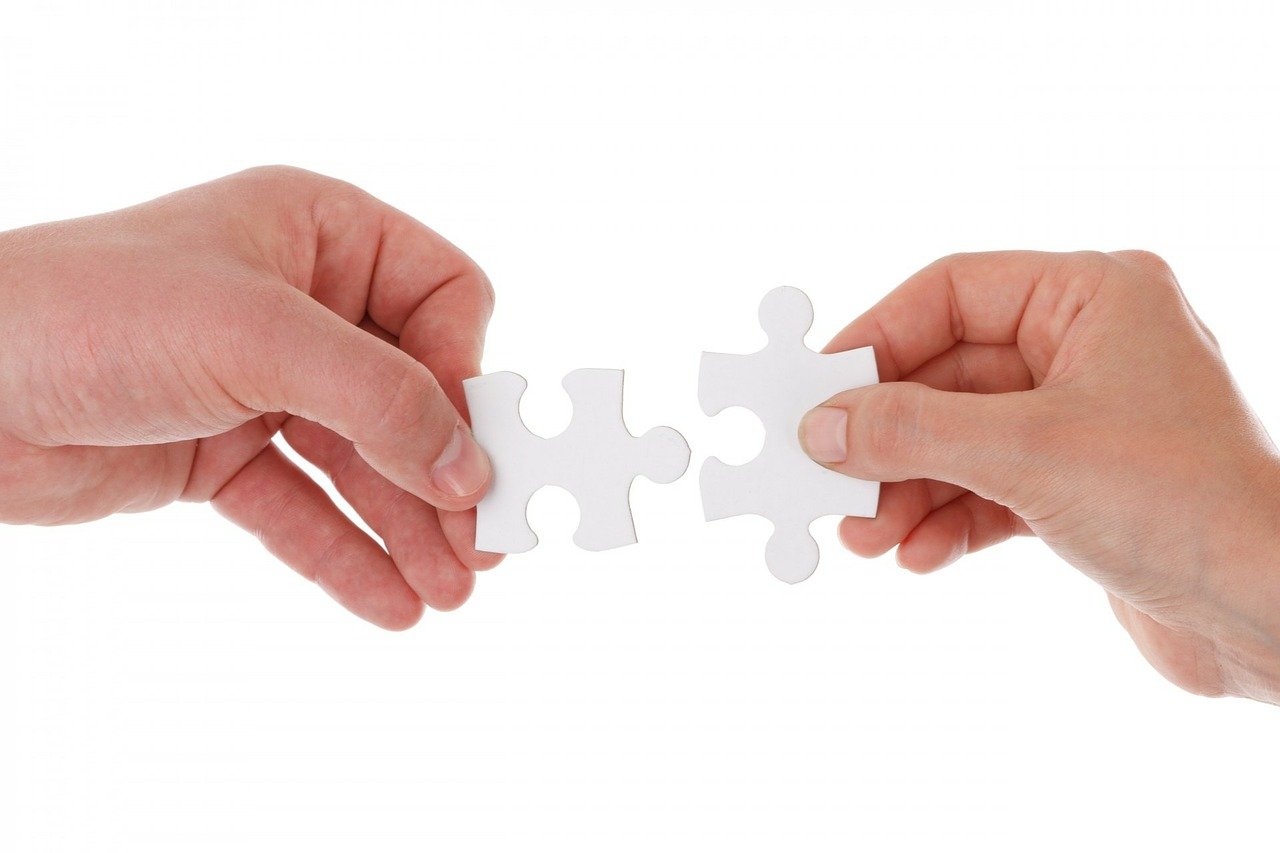 Valokuva, jossa kaksi kättä sovittaa yhteen kahta palanpelin palaa.