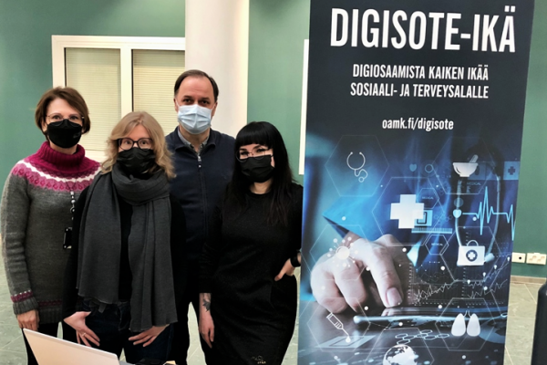 Valokuvassa neljä ihmistä ja taustalla Digisote-ikä-hankkeen posteri.